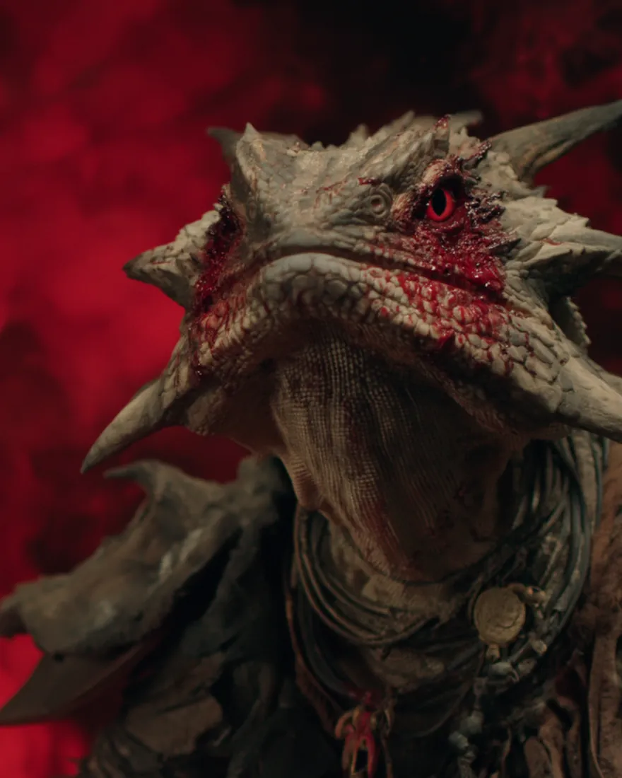 An old Iziak'xak in red smoke, angular and sharp bodied, the scales down the side of the head stained by the blood it shoots from its own eyes.